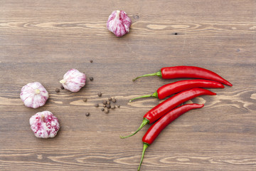 Red chilli pepper and garlic with green basil on wooden table