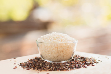 Polished rice heap in small glass with green nature background.