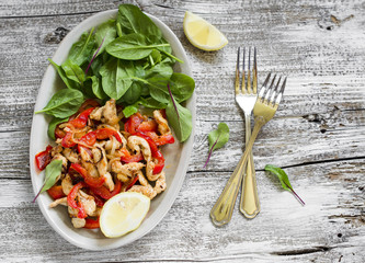 stir fry of chicken breast and sweet red pepper and fresh spinach on a light wooden background
