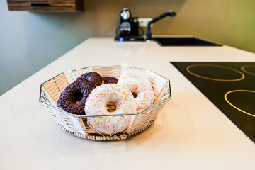 Fresh donuts lying in the basket on the table in the kitchen