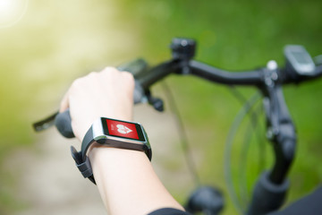 Woman riding a bike with a smartwatch heart rate monitor.