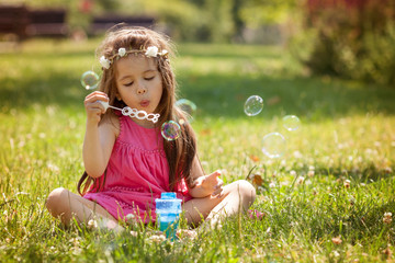 Beautiful portrait of sweet lovely little girl blowing soap bubb