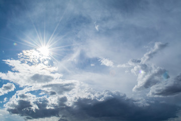 Naklejka na ściany i meble Sun rays against a blue sky in the clouds