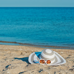 Fototapeta na wymiar Creative hat and sunglasses at the seacoast