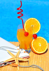 Cocktail with orange and cherry on pool background