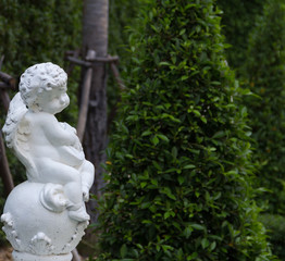 Obraz premium Cupid statue on the white ball in the park.