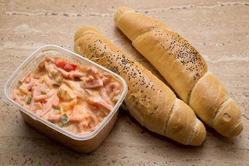 Mayonnaise snack salad in plastic crucible with rolls. Typically fast-food of workers or poors in Eastern Europe.