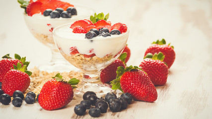 Strawberries, blueberries and breakfast cereal in yogurt on a wo