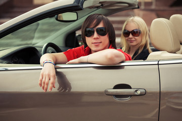 Happy young couple driving convertible car