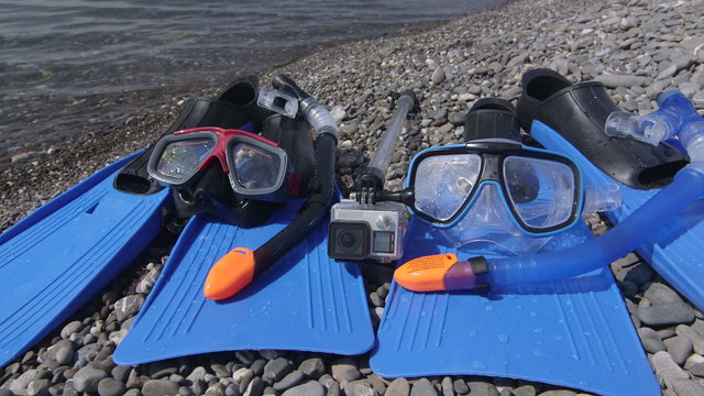 Two snorkeling sets and underwater digital camera on wild pebble beach