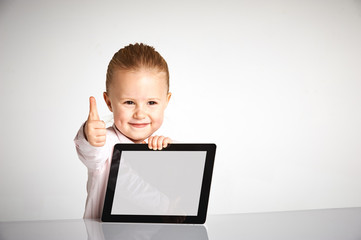 Cute little and smiling girl plays with a tablet