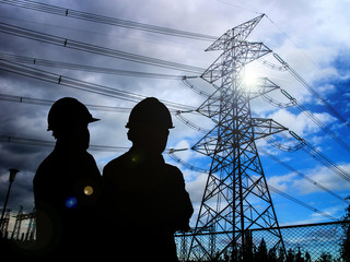 silhouette of engineers standing at electricity station