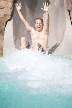 Man Enjoying a wet ride down Water Slide at a water park