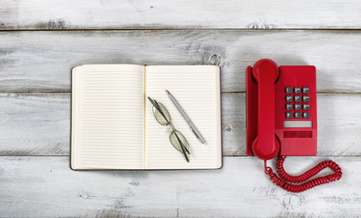Vintage red phone and notepad with pen and reading glasses on ru
