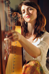 Woman plays celtic harp in folk style
