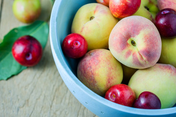 Juicy peaches and apricots in wooden bowl