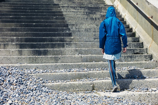 Person in blue jacket walking up stairs outside