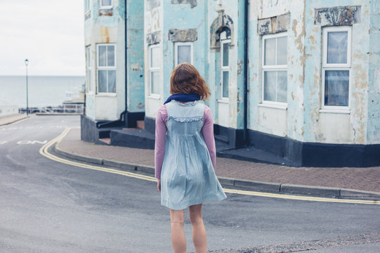 Woman standing in street outside blue house
