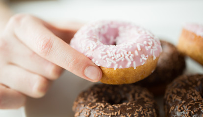 close up of hand holding glazed donut