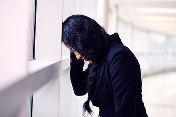 Stressed woman putting her forehead on the office wall