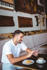 Young man having cup of coffee and pastry