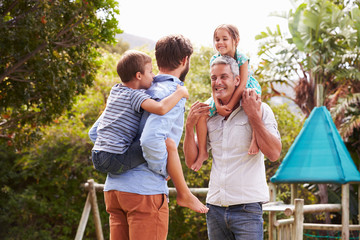 Fototapeta premium Two men piggybacking kids in a garden