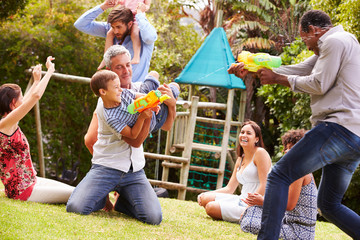 Adults and kids having fun with water pistols in a garden