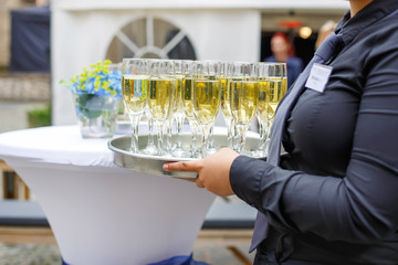 Waitress with dish of champagne and wine glasses