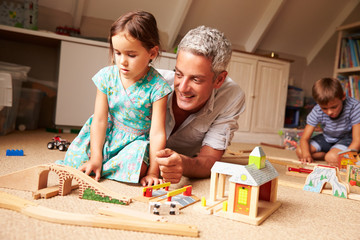 Father playing with kids and toys in an attic playroom