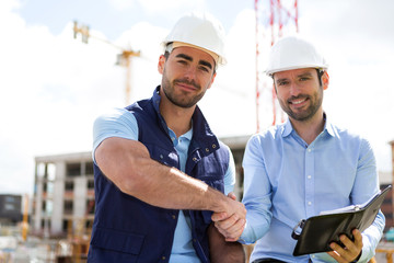 architect and worker handshaking on construction site - obrazy, fototapety, plakaty