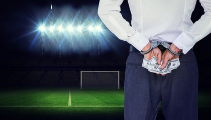 Composite image of businessman in handcuffs holding bribe