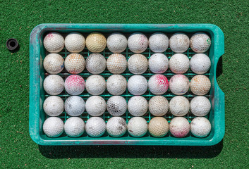 Grunge golf balls in tray on green