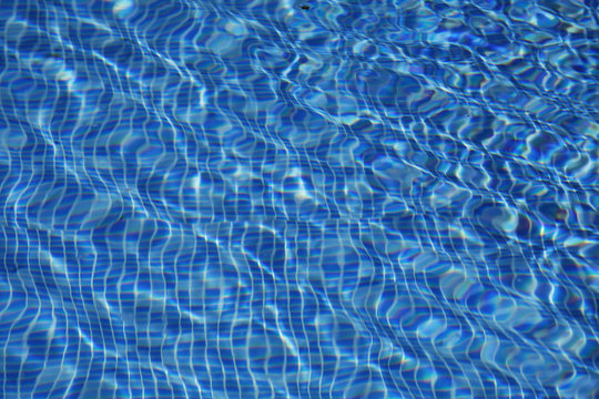 Sun reflected in the swimming pool water as a background