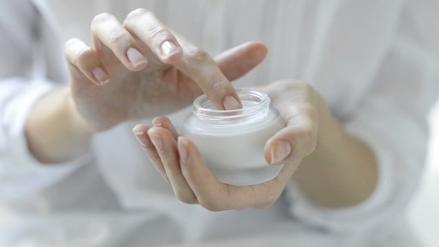 Beautiful woman hands applying moisturizer