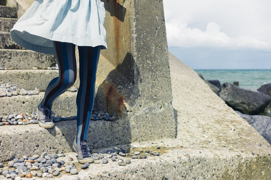 Legs of woman in dress standing on coast