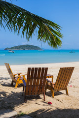 Tropical beach panorama with deckchairs, boats and palm tree