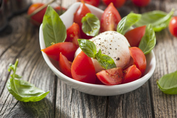 Mozzarella cheese with basil and tomatoes in a bowl