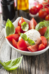 Mozzarella cheese with basil and tomatoes in a bowl
