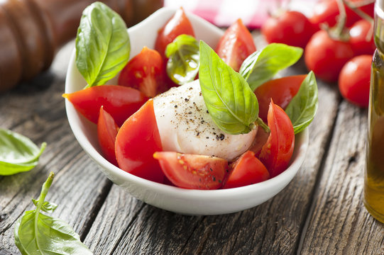 Mozzarella cheese with basil and tomatoes in a bowl