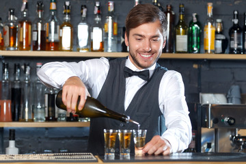 Handsome bartender making shots