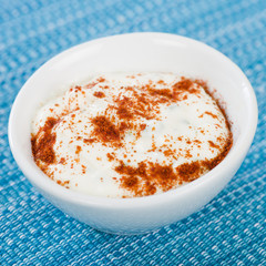 Paprika & Chive Dip - Sour cream and chive dip dusted with smoked paprika on a blue background.
