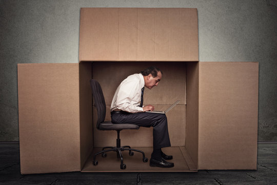 Man Sitting In A Box Working On Laptop Computer