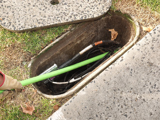 Installer pushing a green Nylon jacketedfiber optic ribbon cable in a duct  at a installation site...