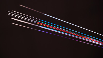 Vivid color coded Optic Fibers with the ends stripped from color in front of a dark background