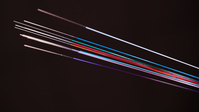 Vivid color coded Optic Fibers with the ends stripped from color in front of a dark background