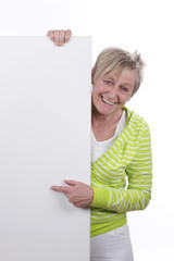 Happy older woman behind a white board