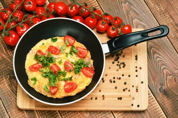 Papier Peint photo Oeufs sur le plat Omelette with ham, tomatoes and chees on the frying pan.
