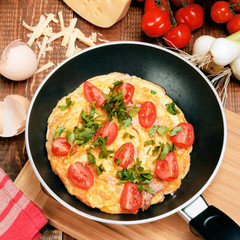Omelette with ham, tomatoes and chees on the frying pan.