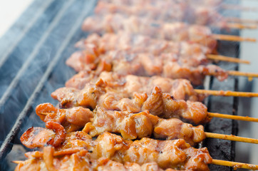 Skewer chicken pieces roasting on the grill and smoke
