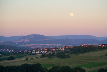 Fototapeta premium Altenriet mit Albtrauf / Jusi im Abendlicht + Mond